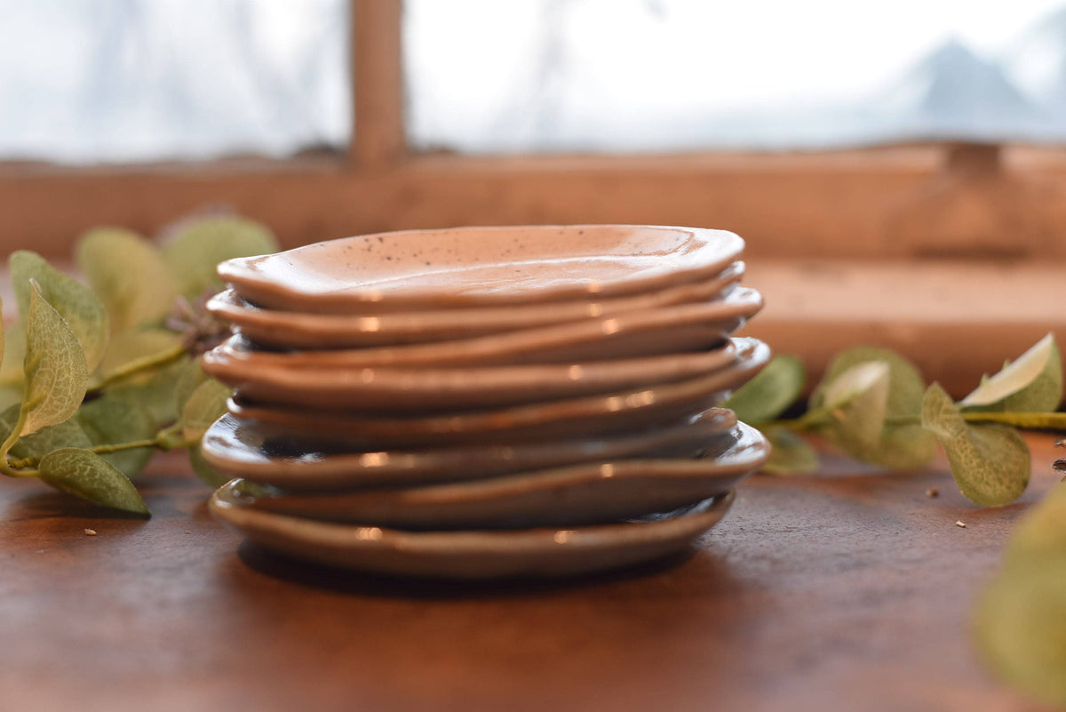 Stack of ceramic plates on a wooden surface with greenery