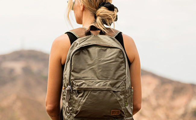 Person wearing a green backpack with a mountainous landscape in the background
