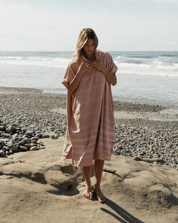Woman standing on a rocky beach wearing Pink Sand Cloud Border Classic Stripe Poncho 