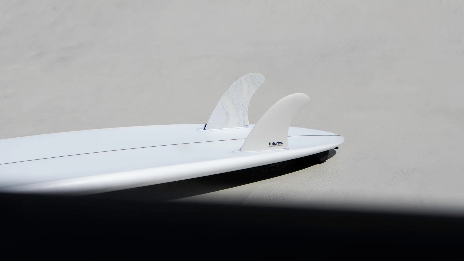 Close-up of a white surfboard with Futures Son Of Cobra Fiberglass Twin Fin Set