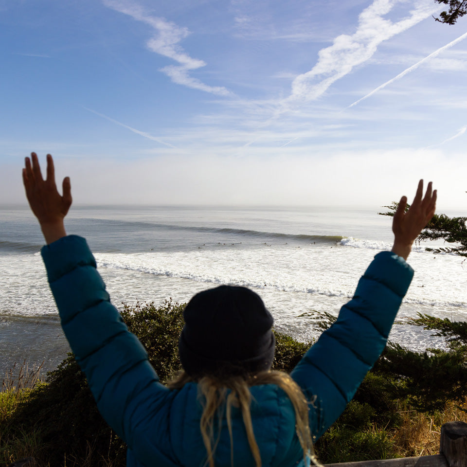 woman holding her hands up to the surf